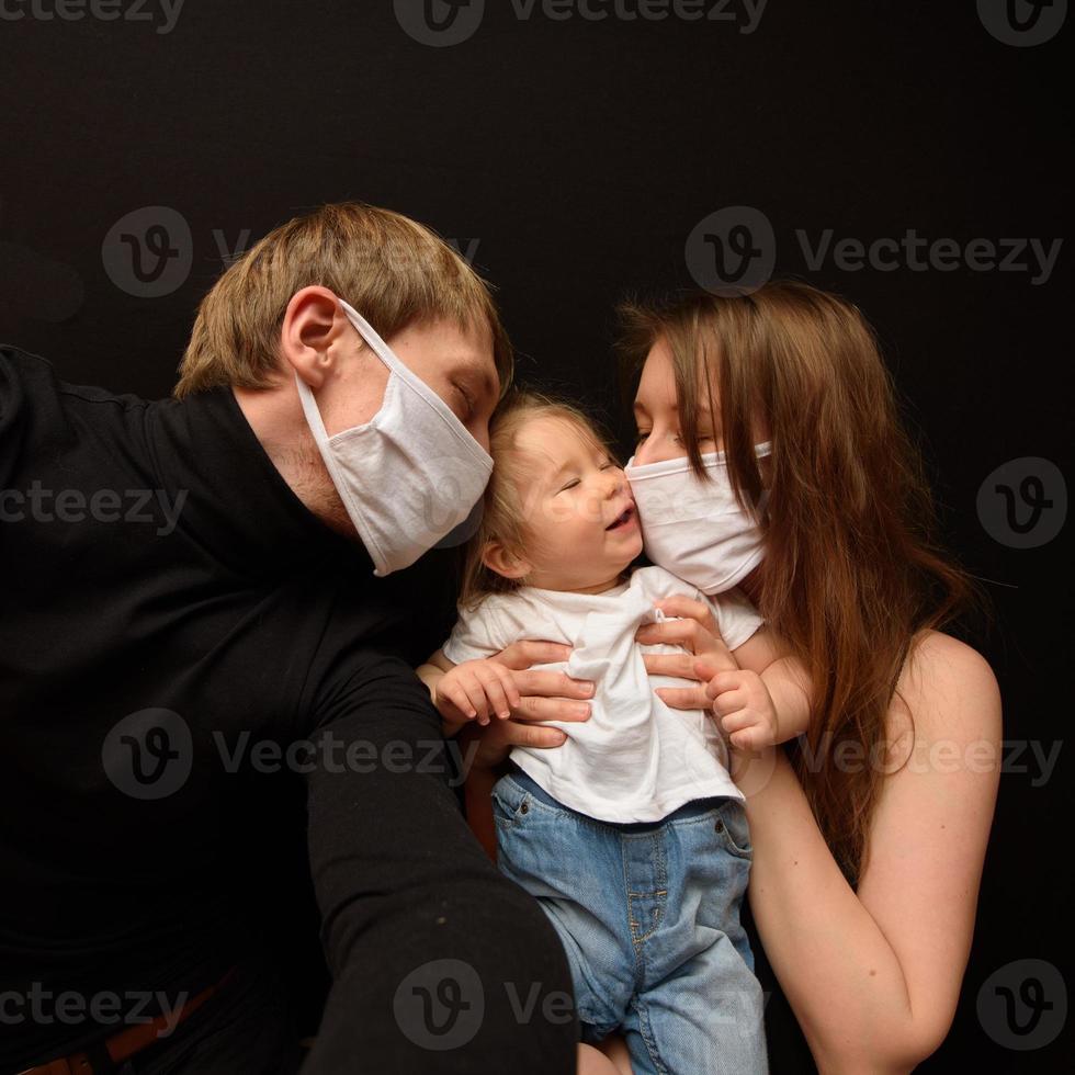 Masked parents take selfies with their little daughter. photo