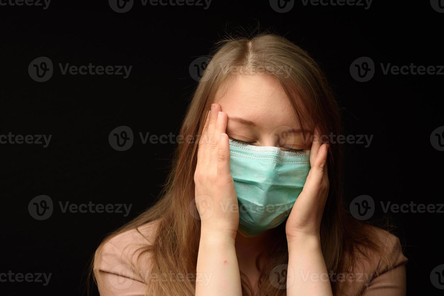 The girl in the medical mask shows the symptoms of the disease. photo