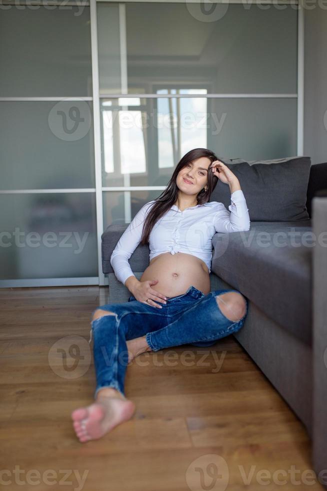 A man and a pregnant woman are sitting hugging on the couch. photo