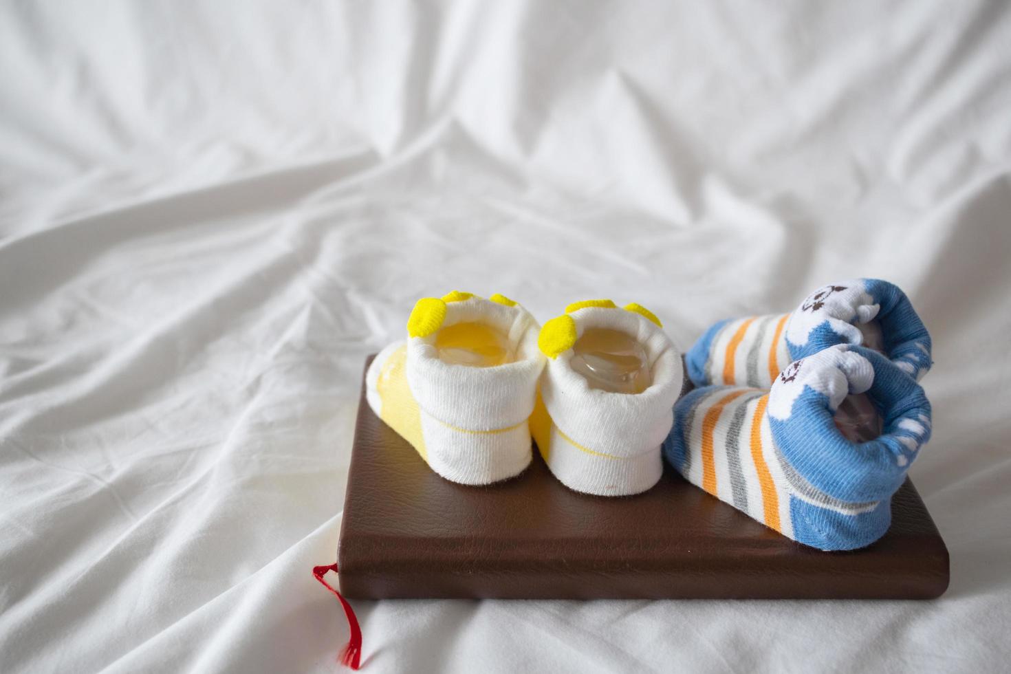 enfoque suave y enfoque suave, dos pares de zapatos recién nacidos sobre un libro en el dormitorio de la futura madre son los zapatos del bebé que compró para su bebé y estaba esperando ver la cara de su bebé. foto