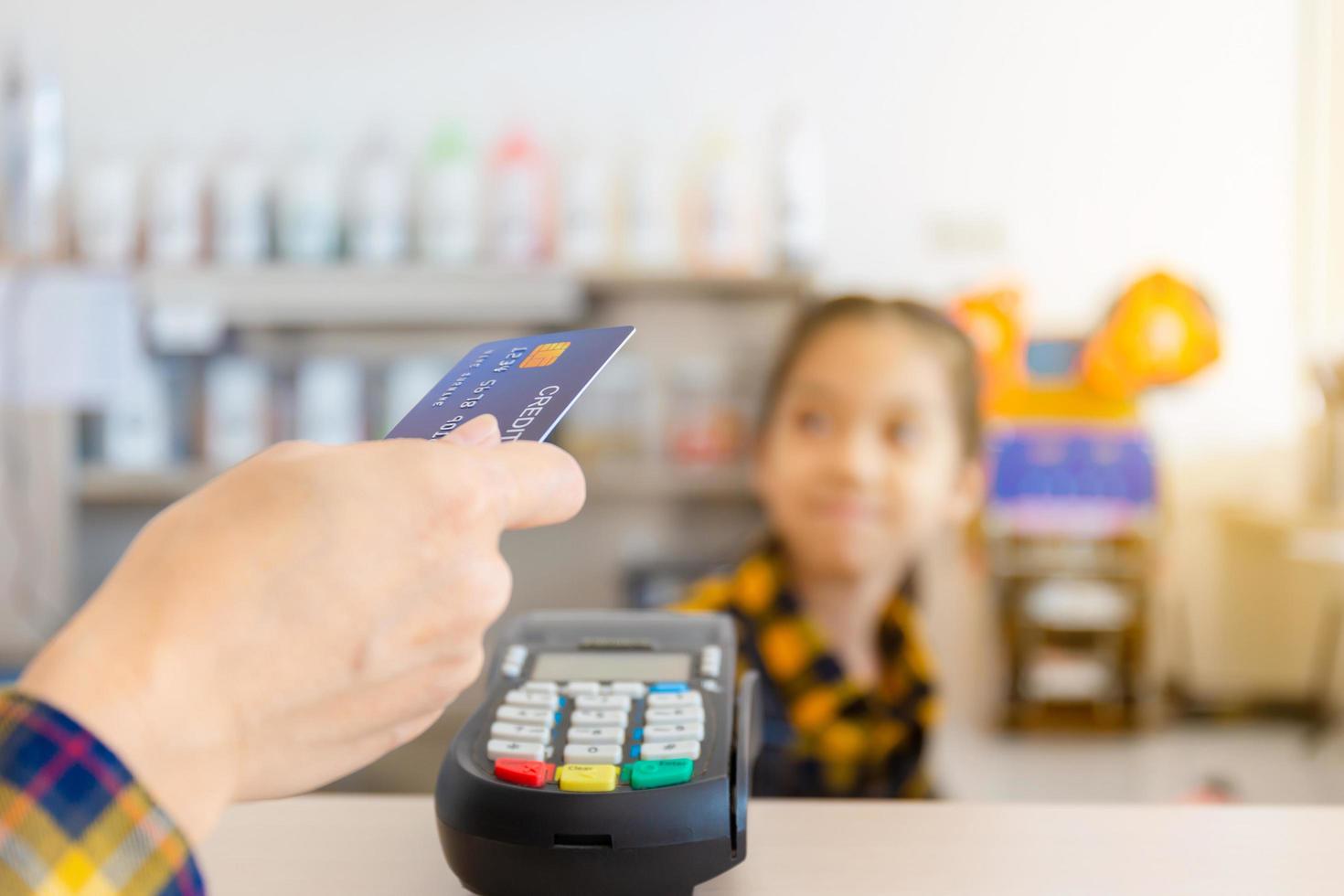 Hand of customer with credit card blurred credit card reader machine at bar counter, payment concept photo