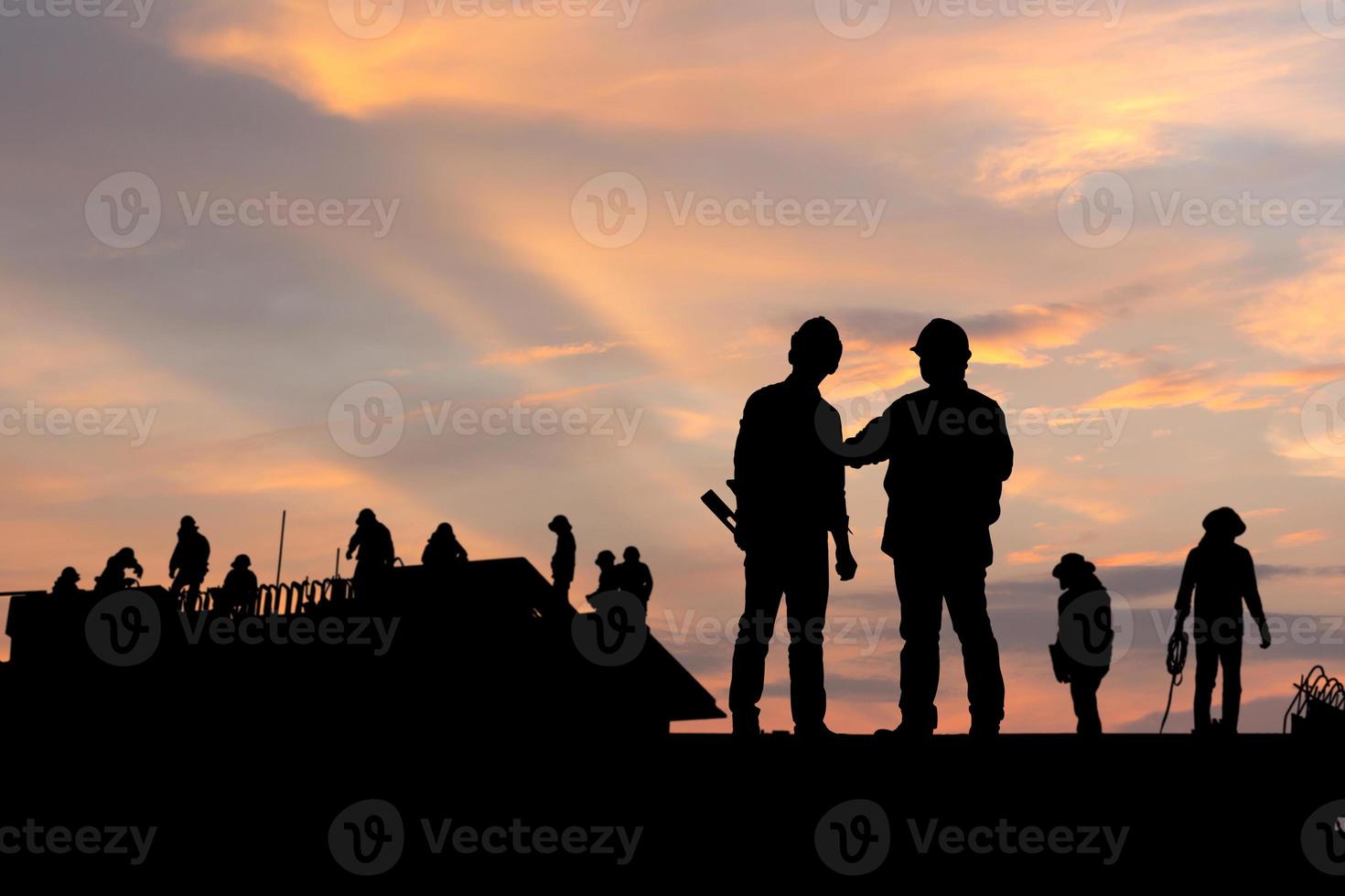 Silhouette of Engineer and worker on building site, construction site at sunset in evening time photo