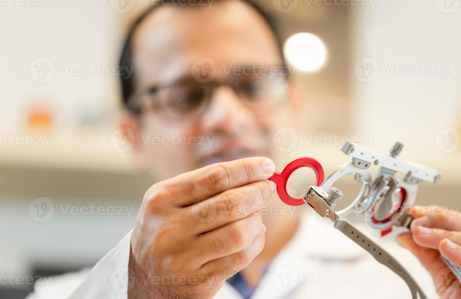 Ophthalmologist with optometrist trial frame in ophthalmological clinic, Optometrist checking trial frame in optical shop photo