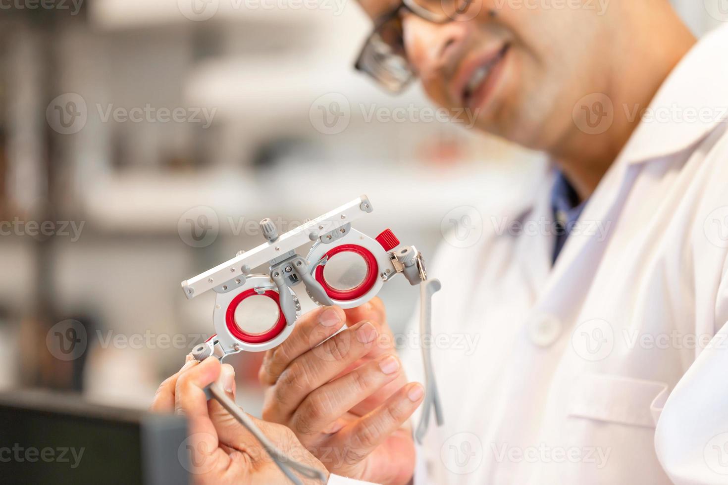 Ophthalmologist with optometrist trial frame in ophthalmological clinic, Optometrist checking trial frame in optical shop photo