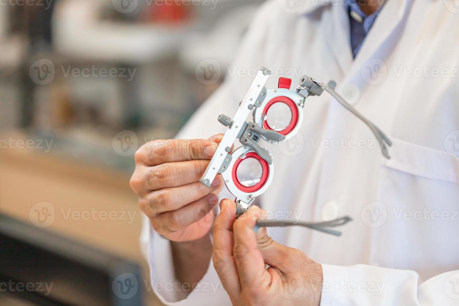 Ophthalmologist with optometrist trial frame in ophthalmological clinic, Optometrist checking trial frame in optical shop photo