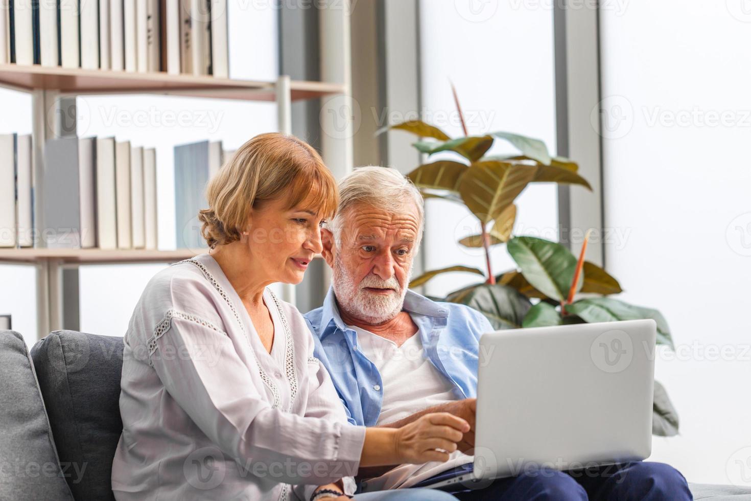 Worried senior couple checking their bills and work on netbook read document information at home, retired elderly old family reading documents with laptop photo