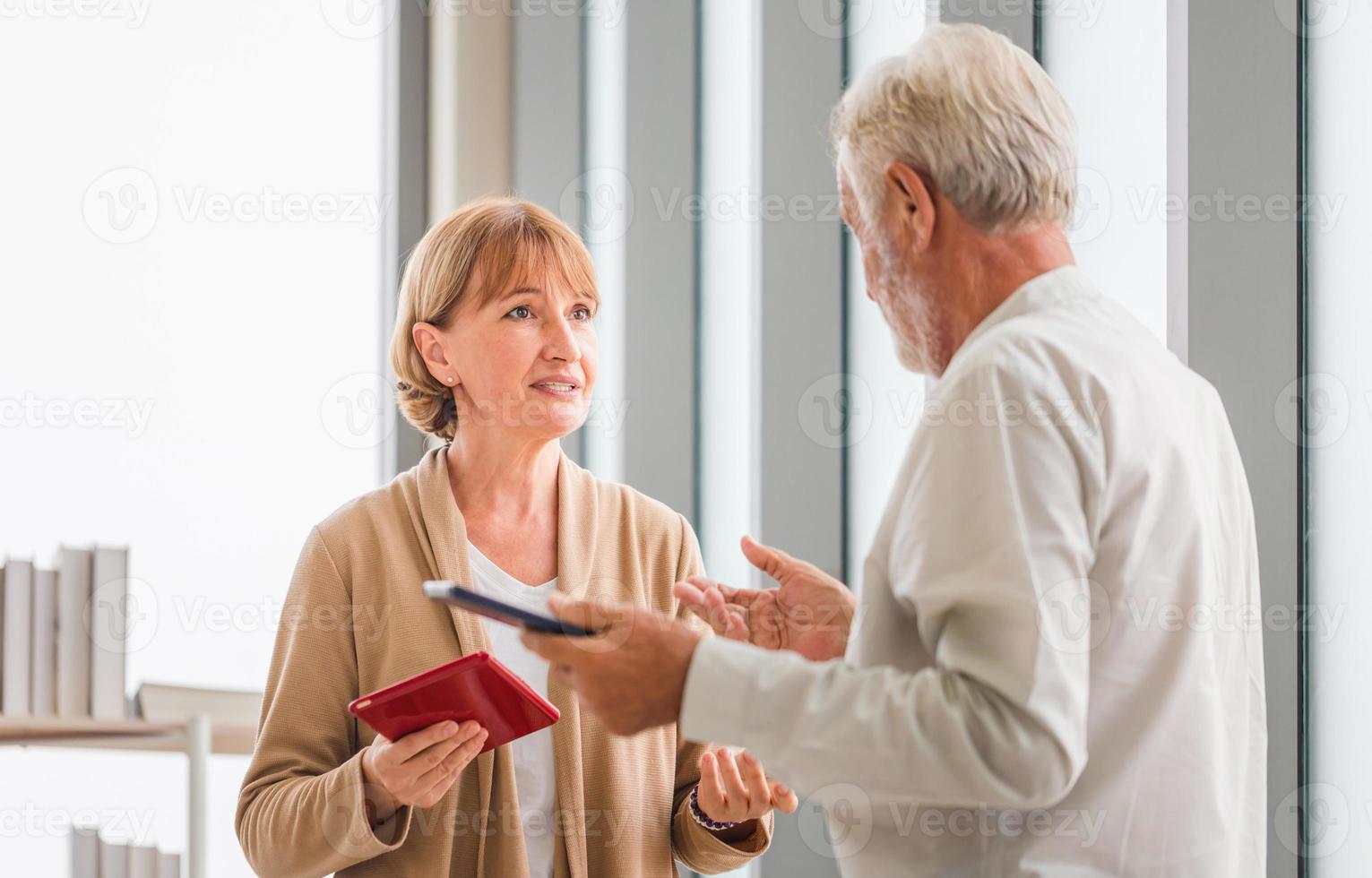 Senior man quarreling with his wife at home, Elderly couple talking while standing near window with cups of coffee photo