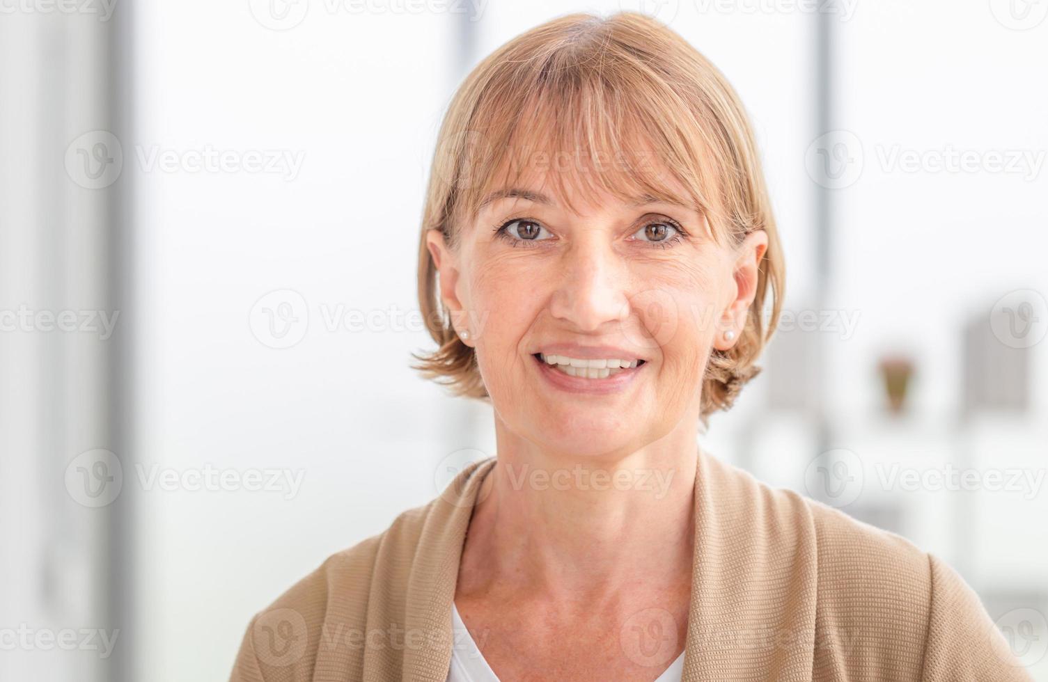 Smiling mature caucasian woman in living room, Portrait of happy woman looking at camera photo