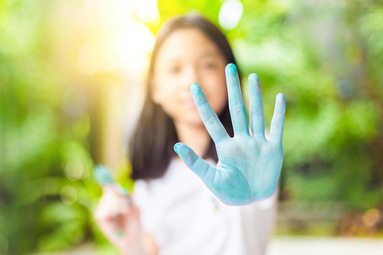 niña divertida muestra las manos sucias con pintura, niña linda y alegre jugando y aprendiendo coloreando los colores foto