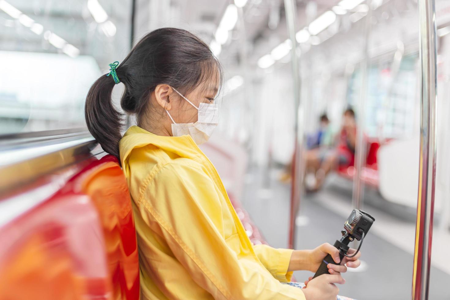 la niña se dispara en la cámara de acción, la niña usa mascarilla durante el coronavirus y el brote de gripe, viaja en tren. foto