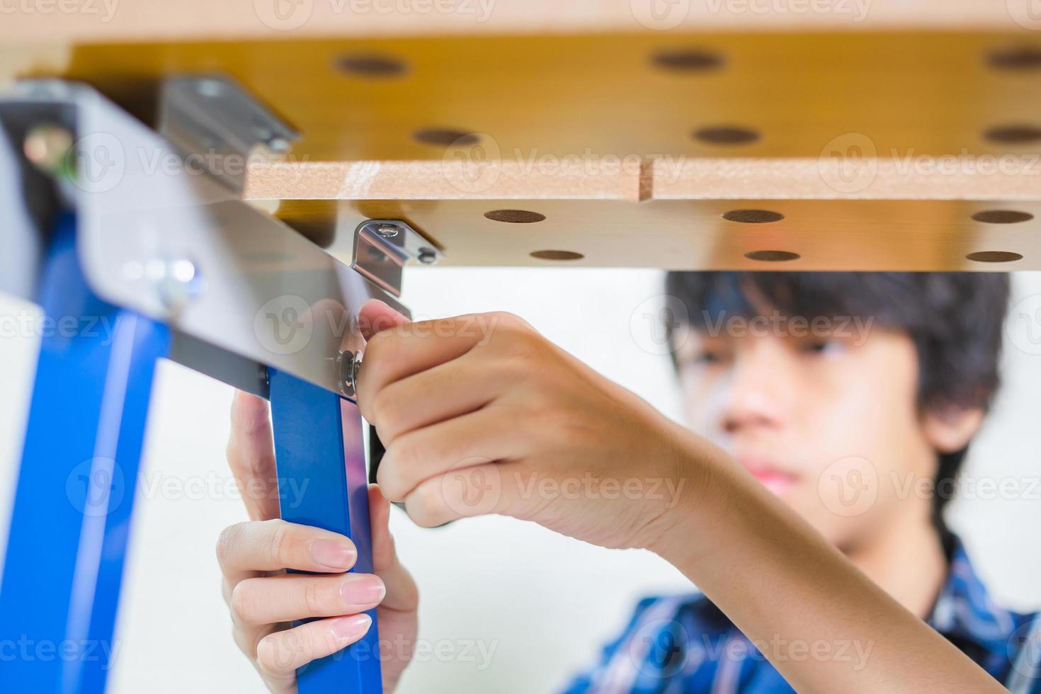 Boy install bolts and nuts of piping in the craftsman workshop, Worker's hand tightens the nut on the bolt photo