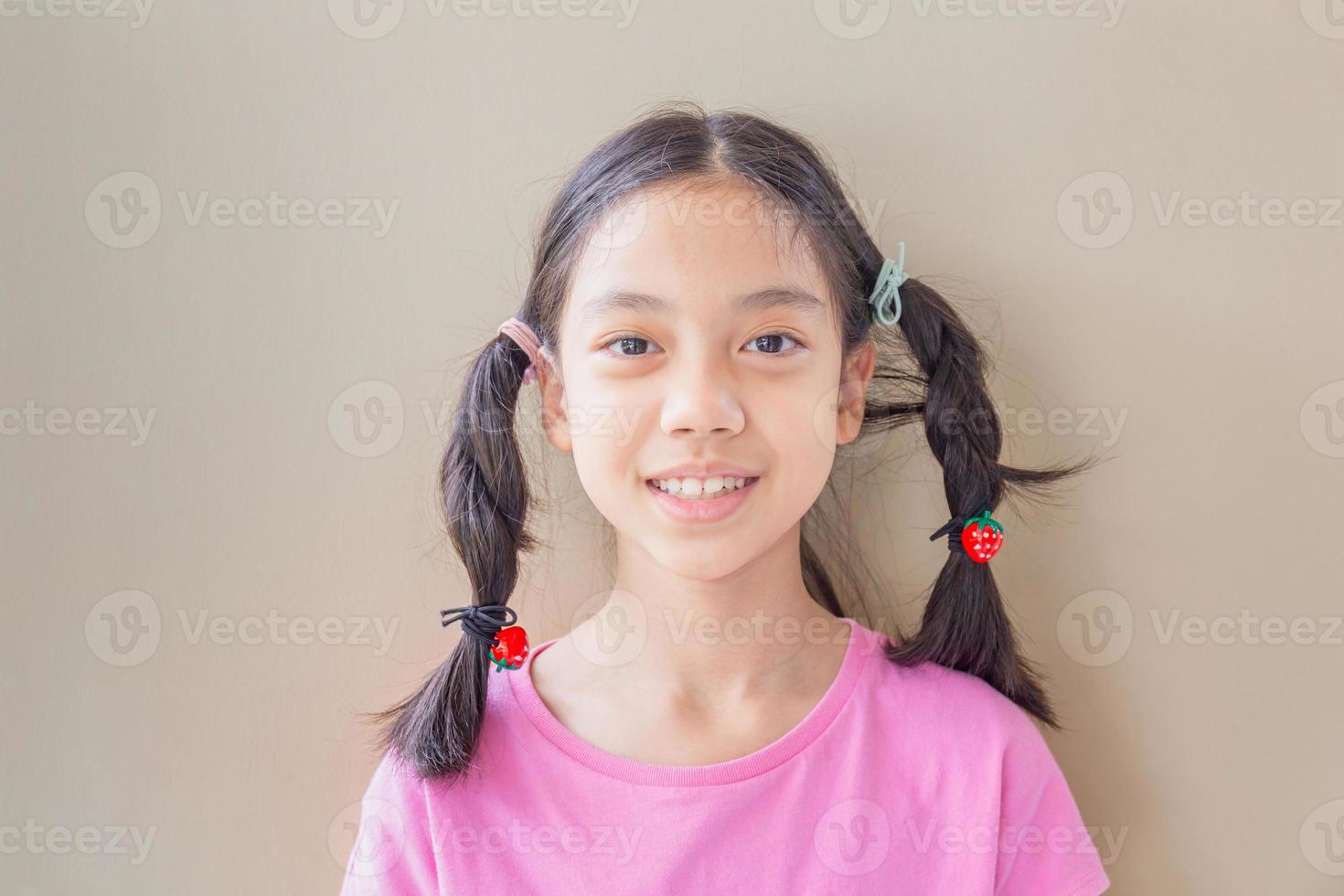 retrato frontal en la cabeza de una niña asiática feliz mirando a la cámara foto