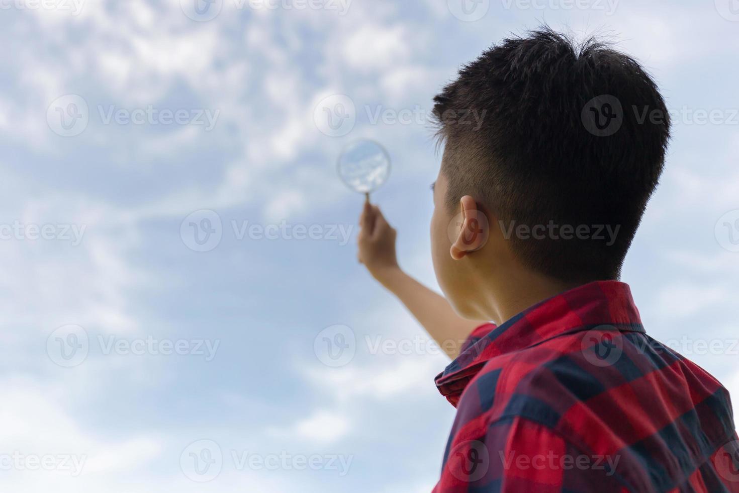 Young boy holding magnifying glass looking sky, Interest planet concepts. photo