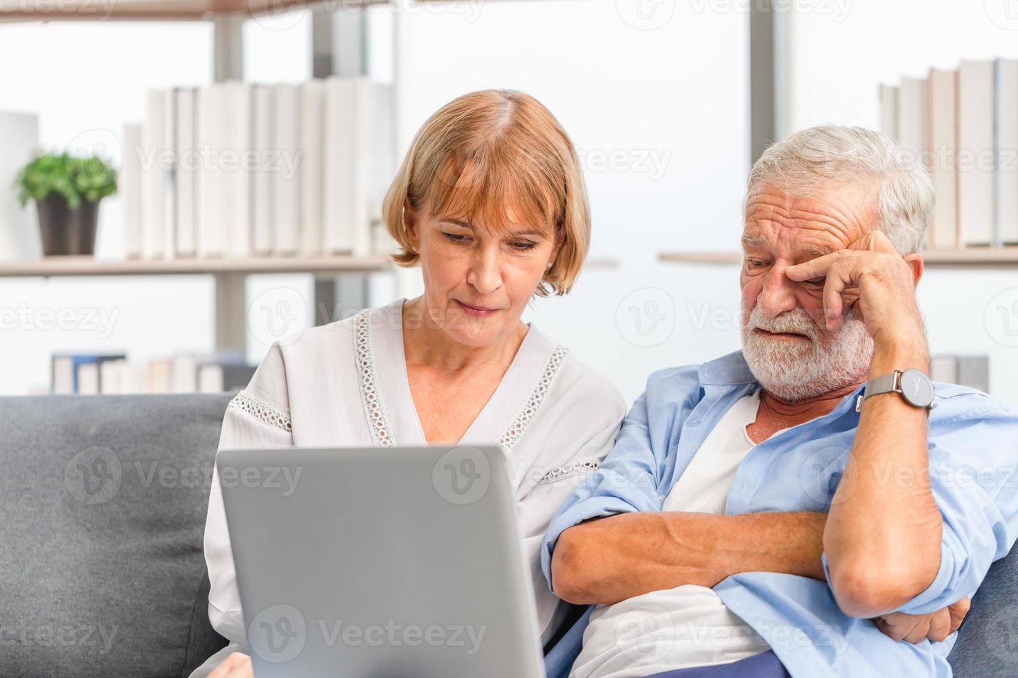 Portrait of Worried senior couple checking their bills and work on netbook read document information at home, Serious retired elderly old family reading documents with laptop photo