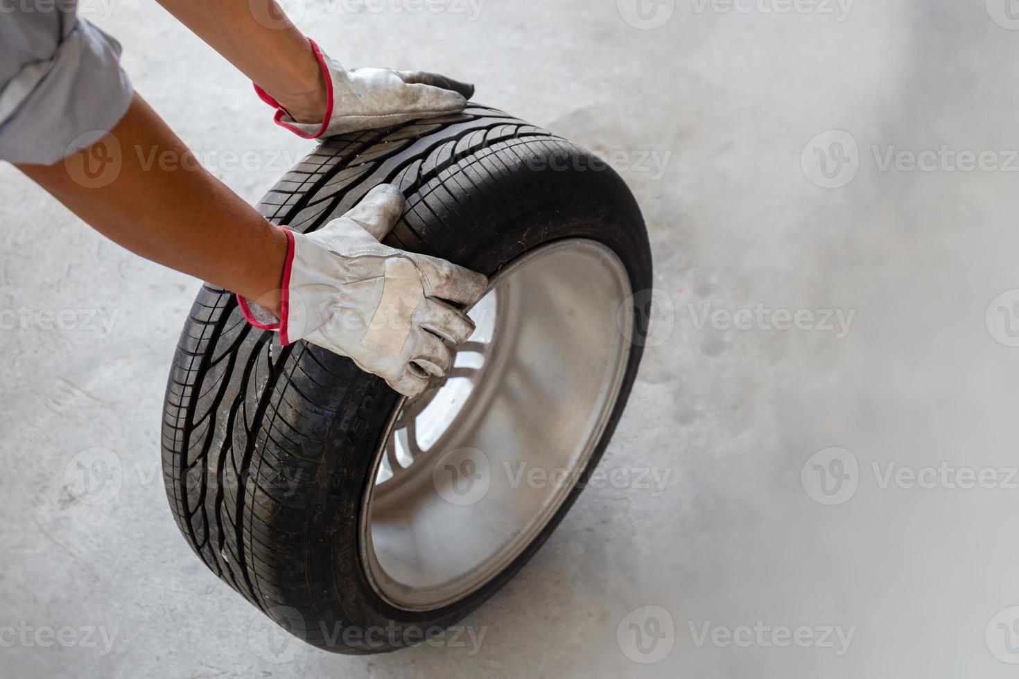 Auto mechanic holding car tire photo