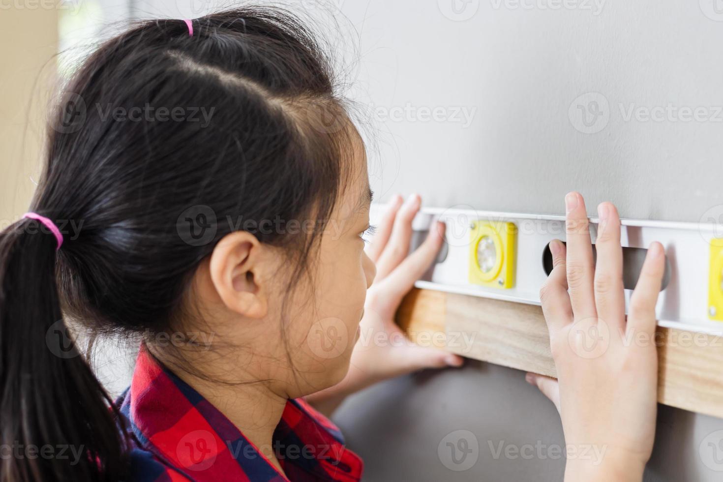 primer plano de niña aprendiendo a usar el nivel de agua de la regla en un taller de carpintería foto