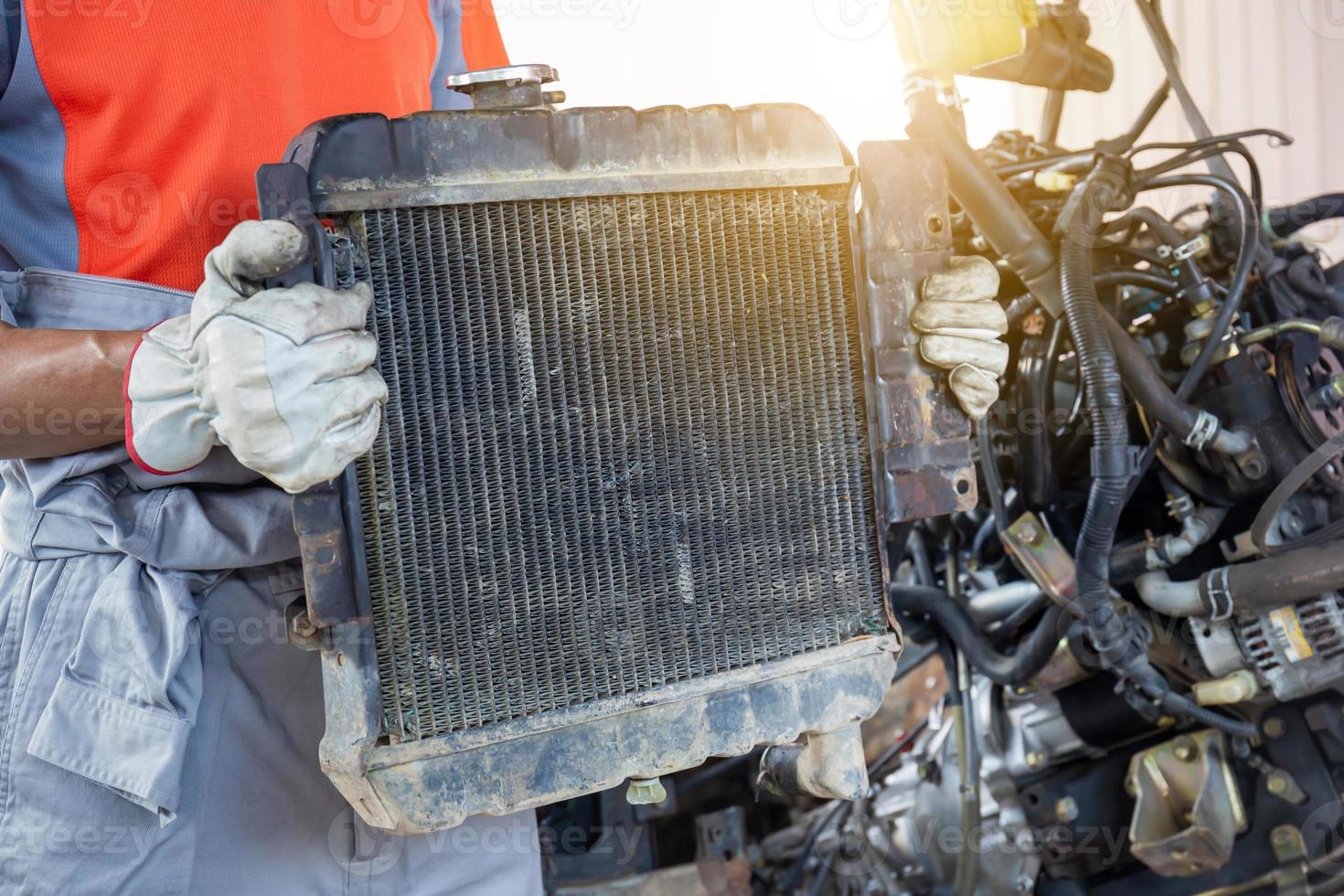 Auto mechanics holding broken car radiator in auto service, technician