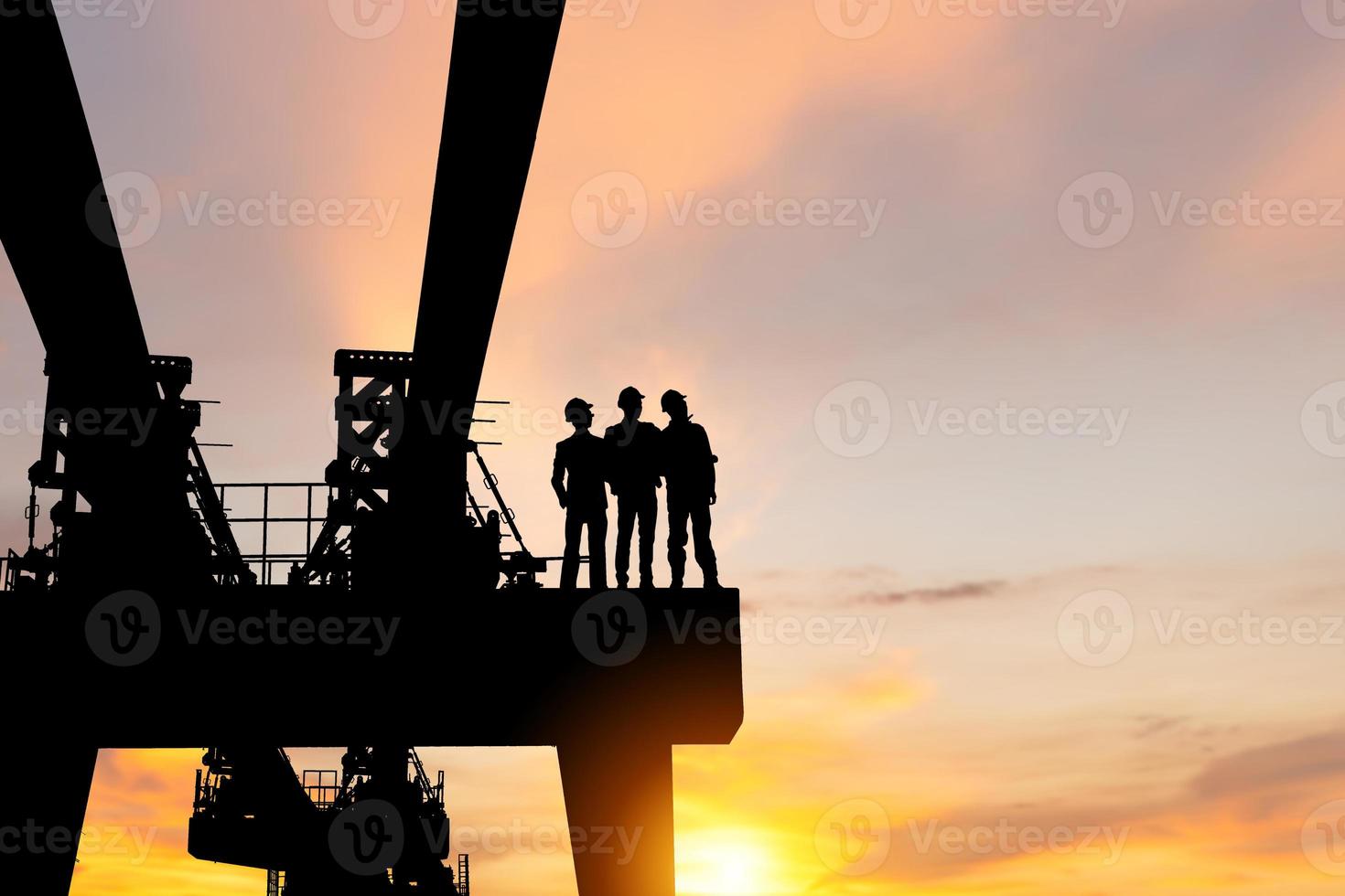 Silhouette of Engineer man team checking project at heavy infrastructure building site background, construction site at sunset in evening time photo