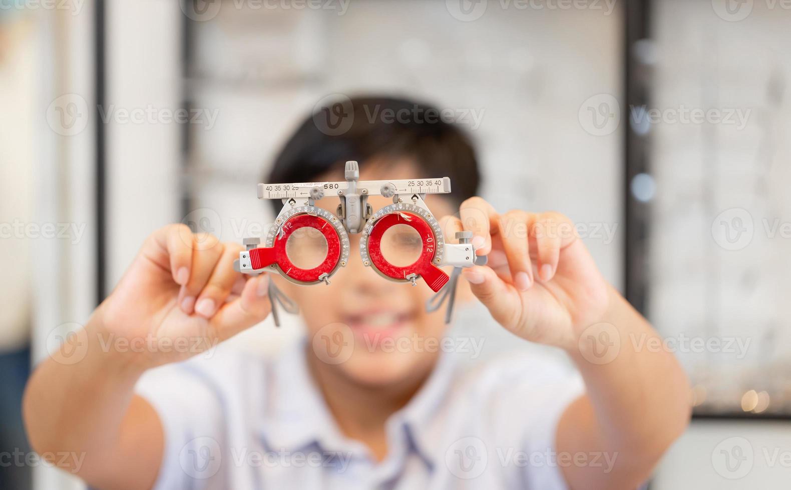 Indian boy with optometrist trial frame in ophthalmological clinic, Boy doing eye test checking examination with optometrist using trial frame in optical shop photo