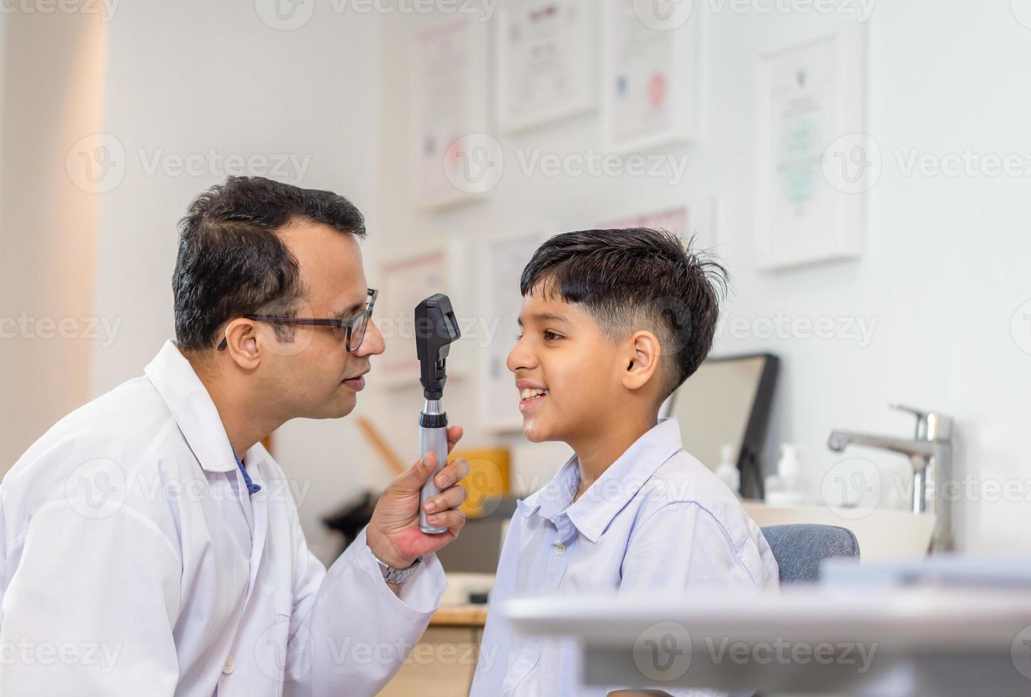Boy doing eye test checking examination with optometrist in optical shop, Smiling Indian-thai boy choosing glasses in optics store photo