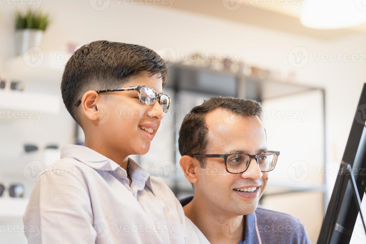 Indian kid and father choosing eyeglasses in optical store, father and son choosing eyeglasses frame in optics shop photo