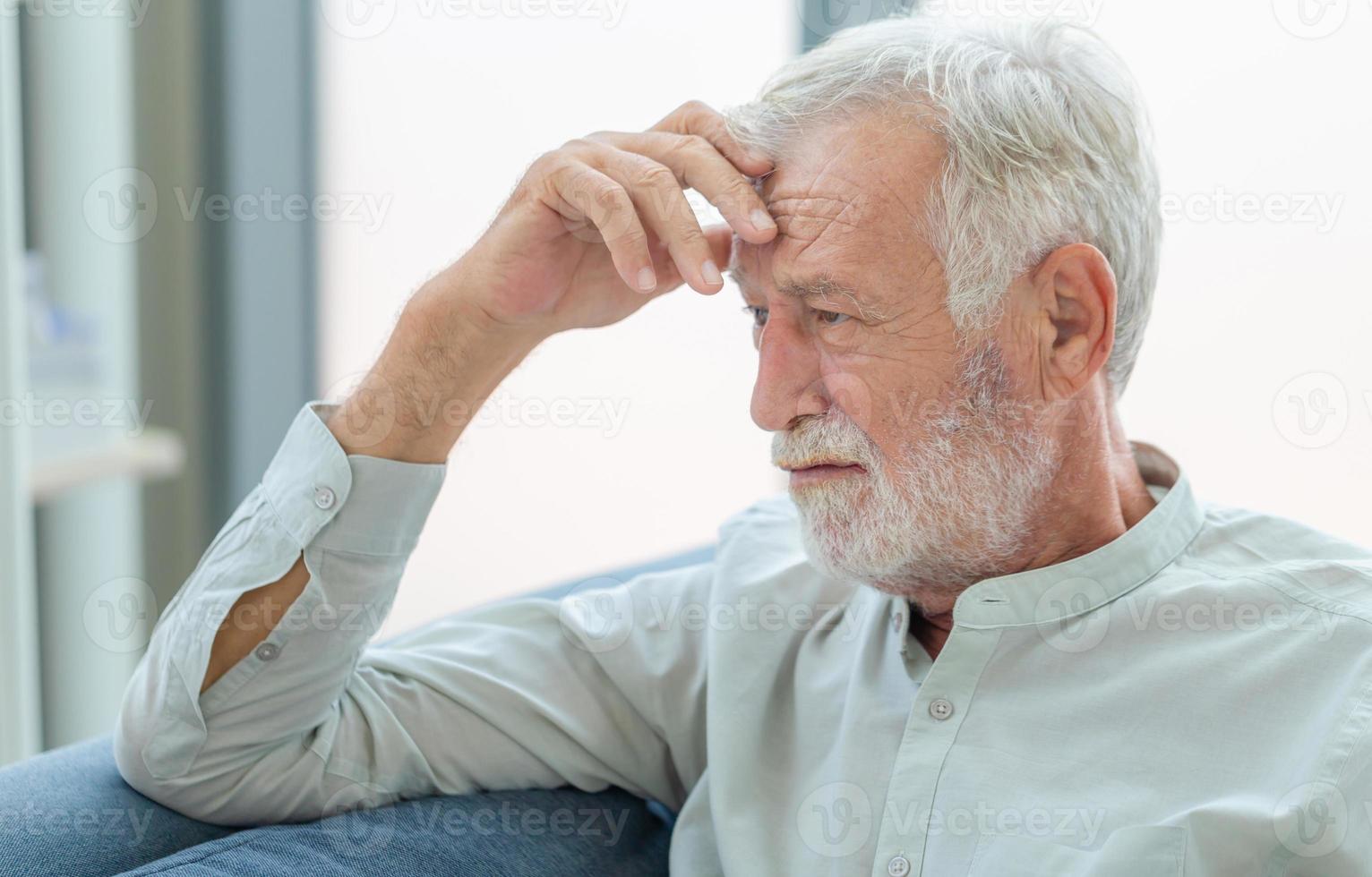 Thinking senior man sit on couch in living room, man thinks and sit on the sofa photo