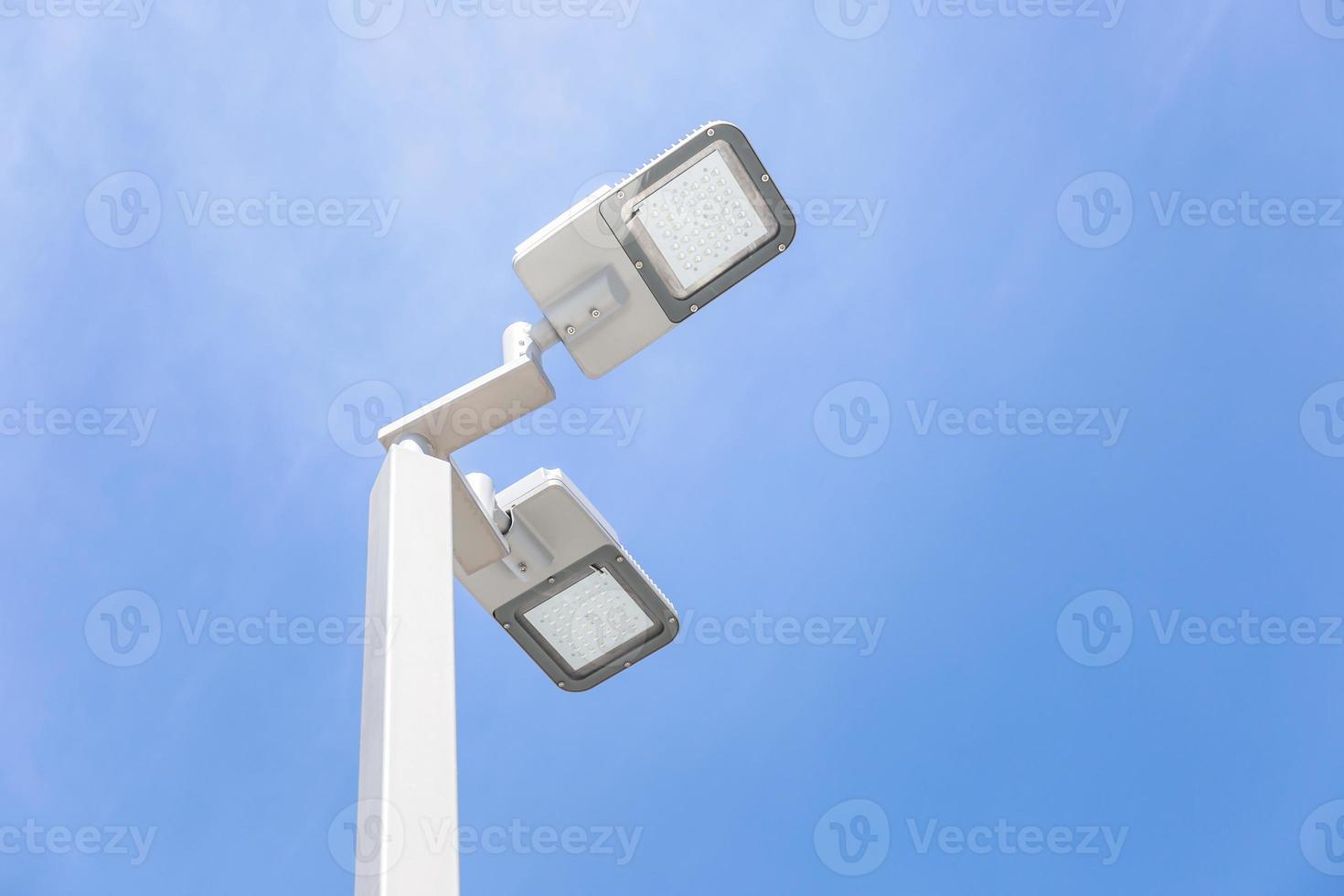 LED street lamp post glowing blue sky with white cloud background. Modern led lights in city photo