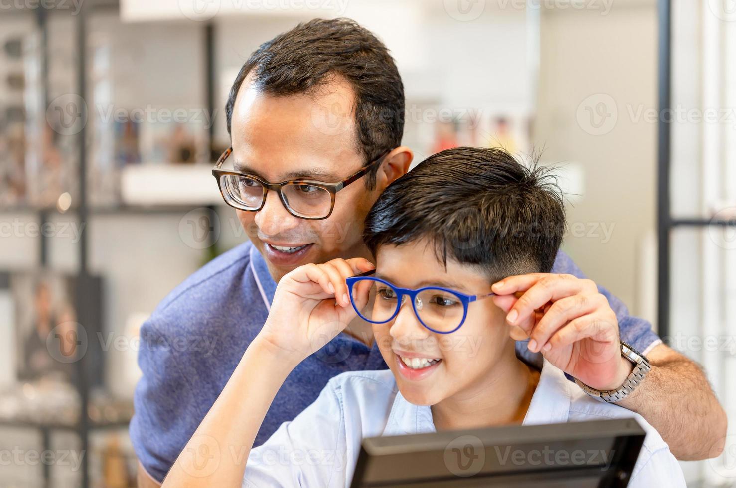 Indian father and son choosing eyeglasses in optics store photo
