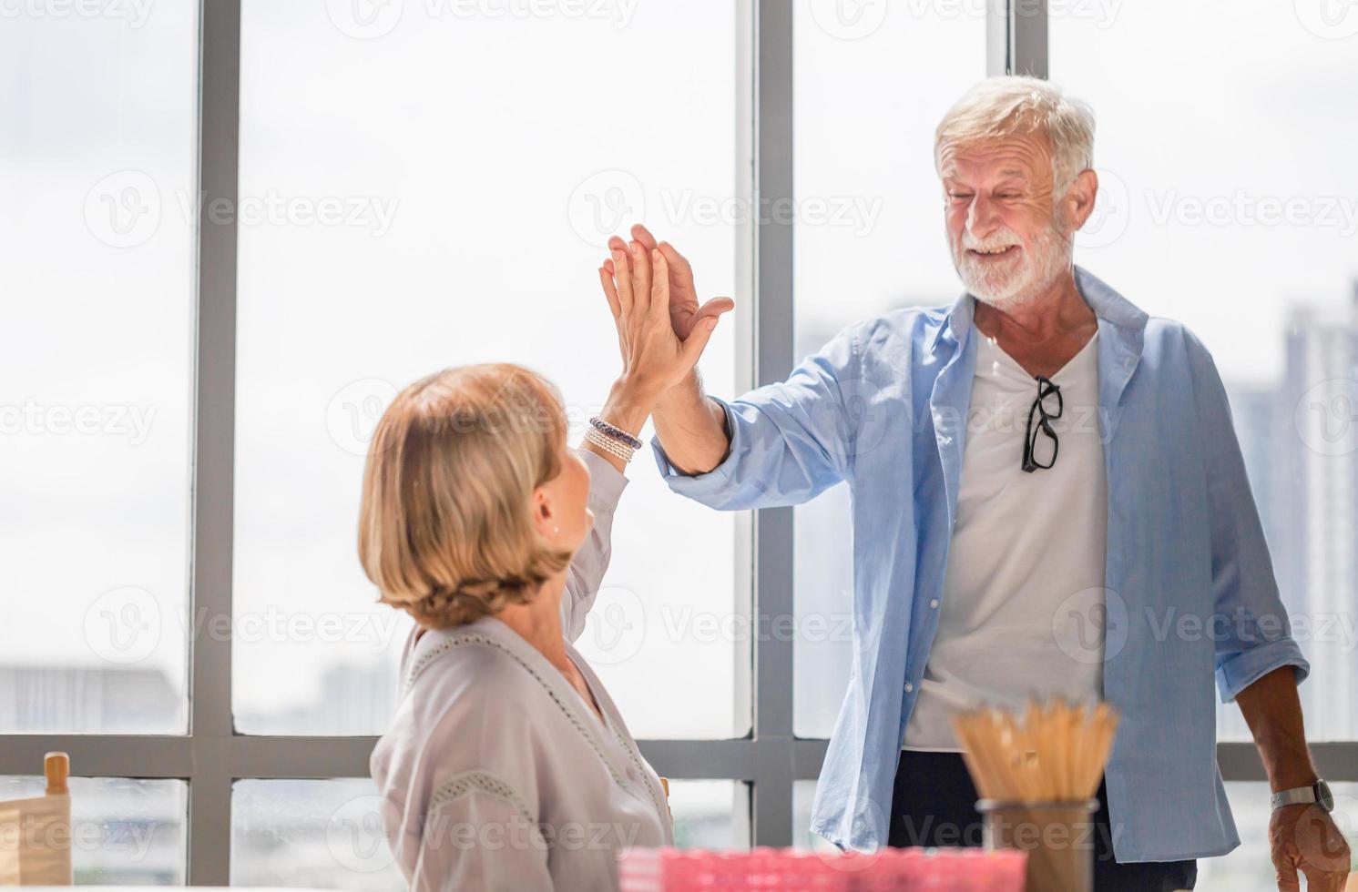 feliz pareja de ancianos en la sala de estar, pareja de ancianos dando cinco, familia feliz y conceptos de jubilación foto