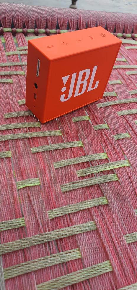 Sialkot, Pakistan - 2021, Red Bluetooth speaker JBL Go standing on carpet photo