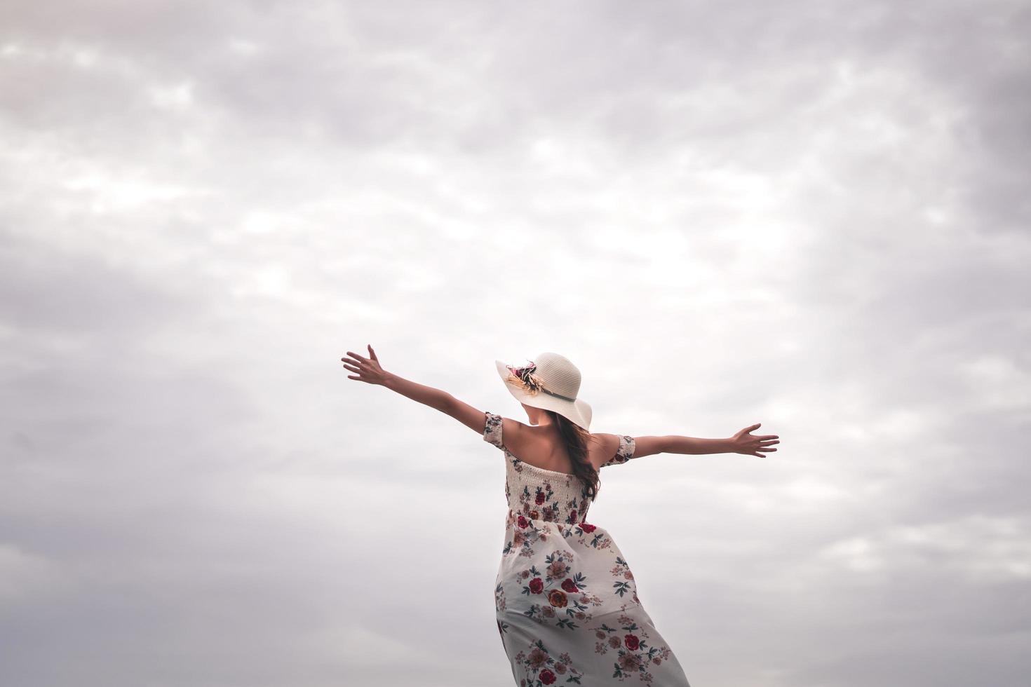 una turista feliz sola disfruta del brazo abierto bajo el cielo. foto