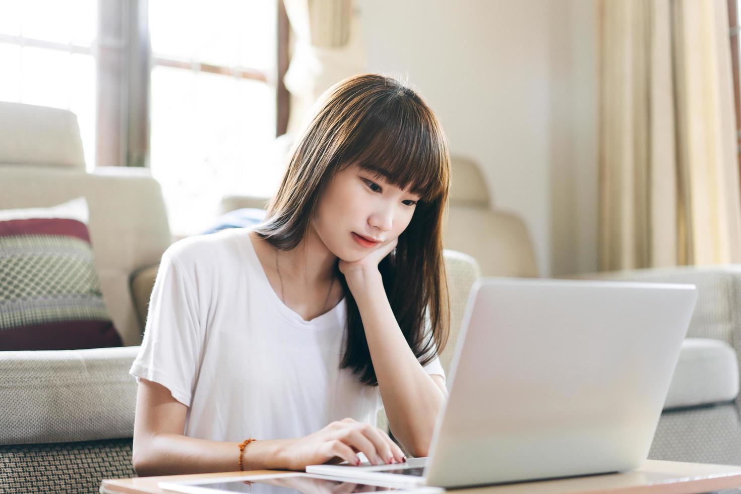 una adolescente asiática trabaja y estudia en línea a través de Internet en casa. foto