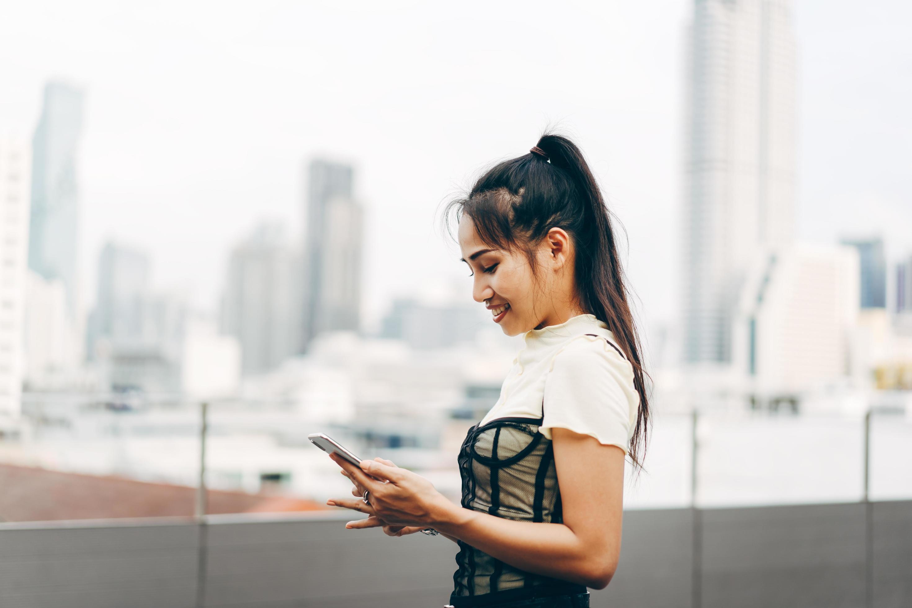 Young business adult asian woman using mobile phone for online dating app text and chat blur city background. 6853838 Stock Photo at Vecteezy