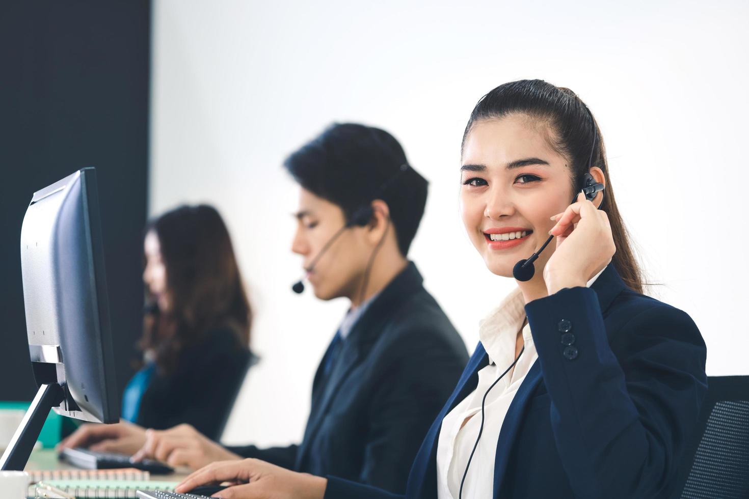 mujer asiática del personal de negocios joven que trabaja con auriculares y computadora para obtener apoyo. foto