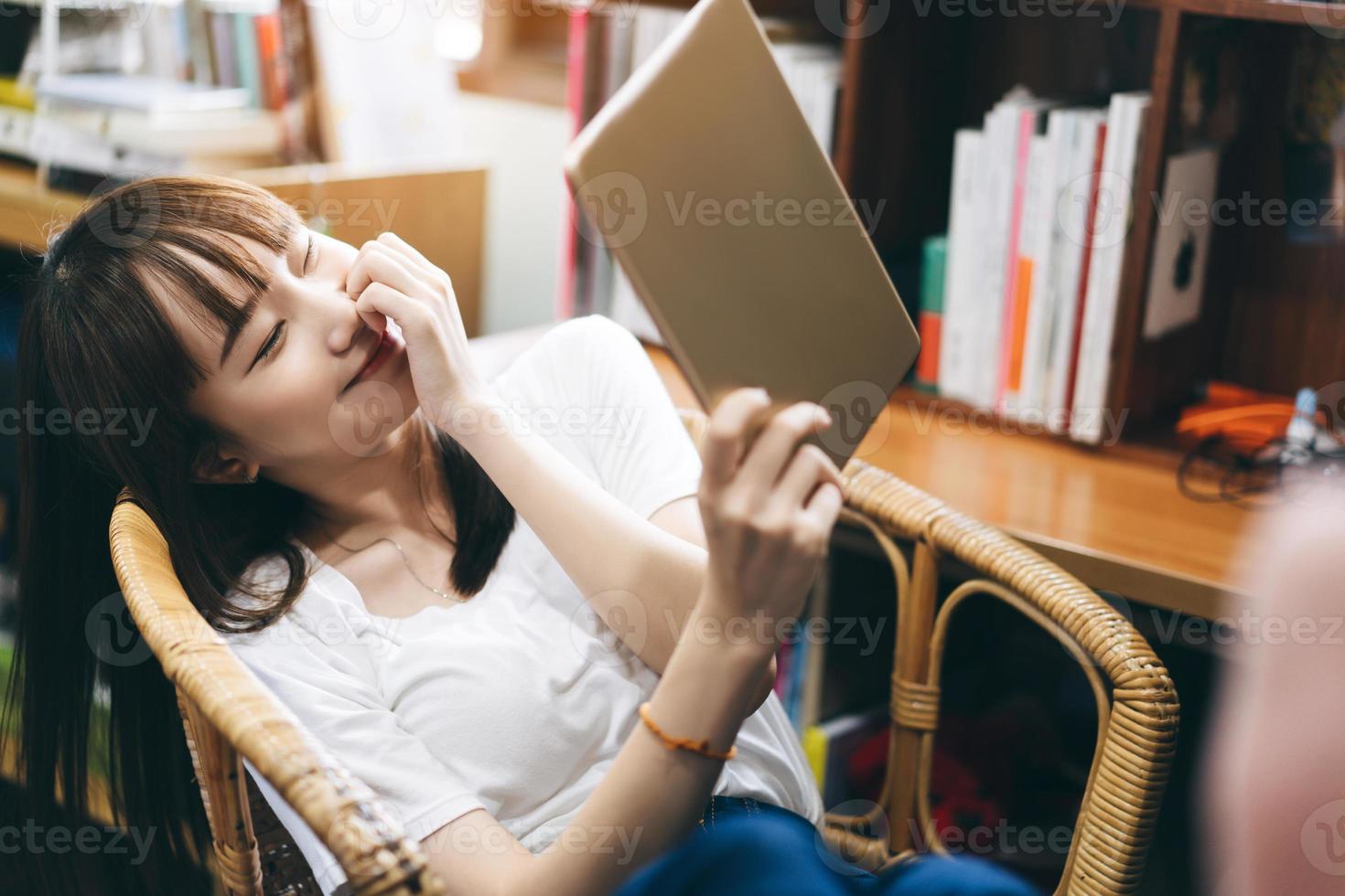 feliz adolescente asiática relaja a la mujer usando tableta para la red social después del trabajo. foto