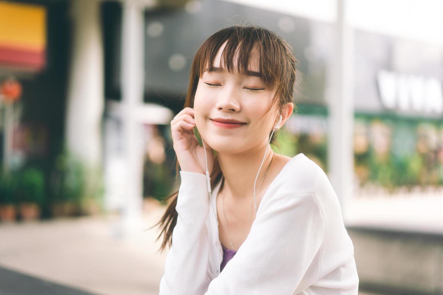 Happy young adult asian woman listening streaming music at outdoor on day. photo