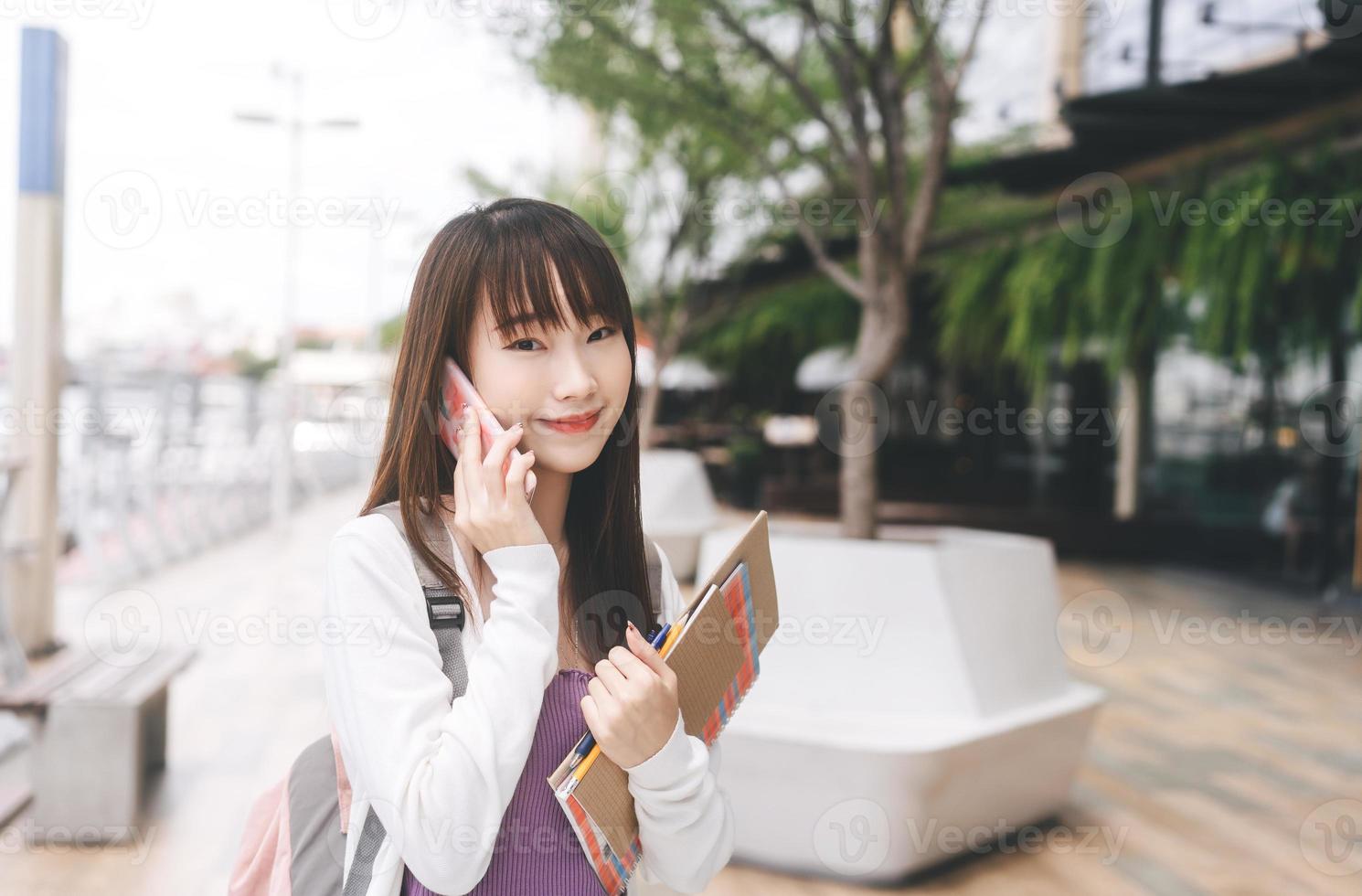 Portrait of happy young adult asian student woman lifestyle using mobile phone on day. photo