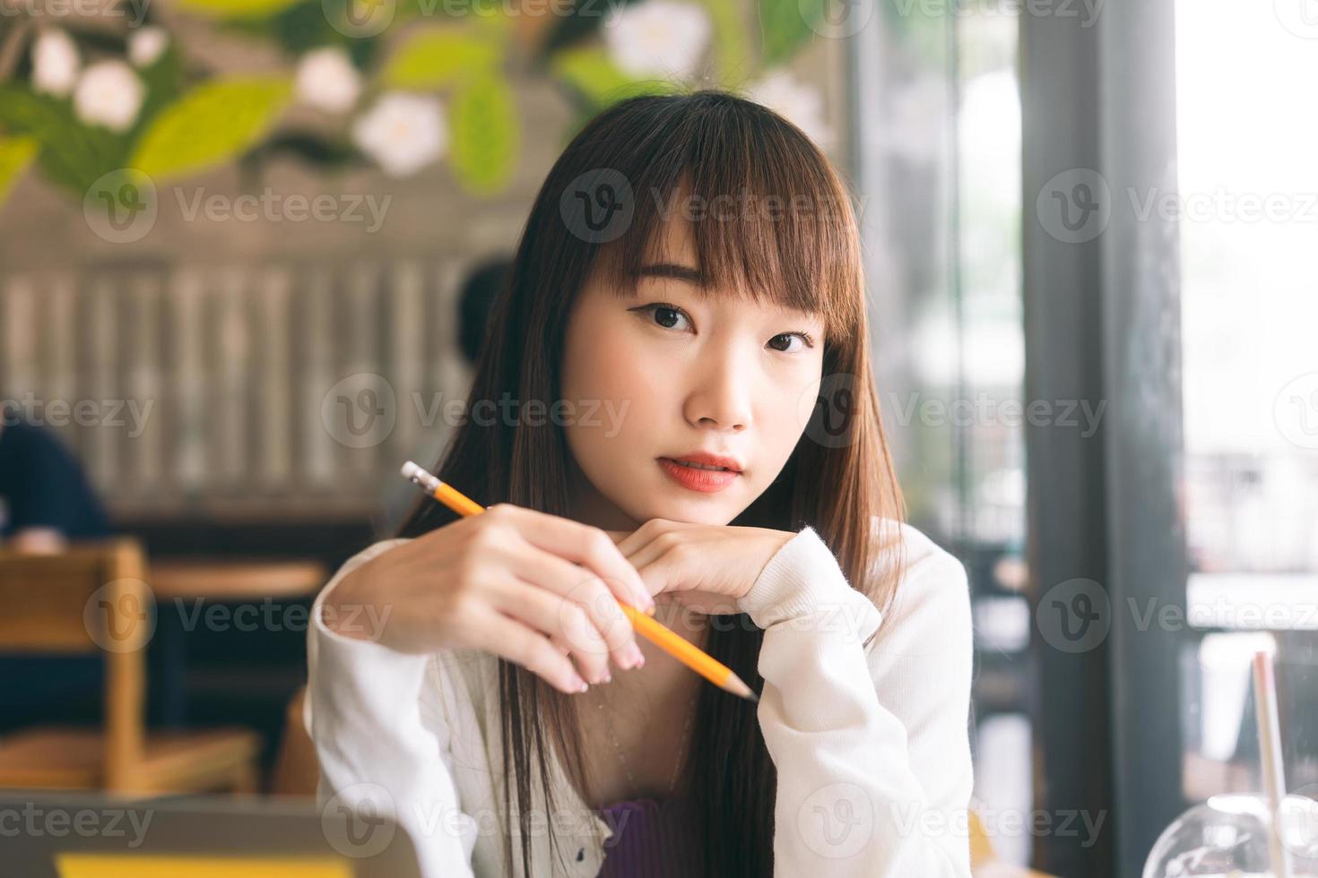 retrato de una joven estudiante universitaria asiática que estudia en un café. foto