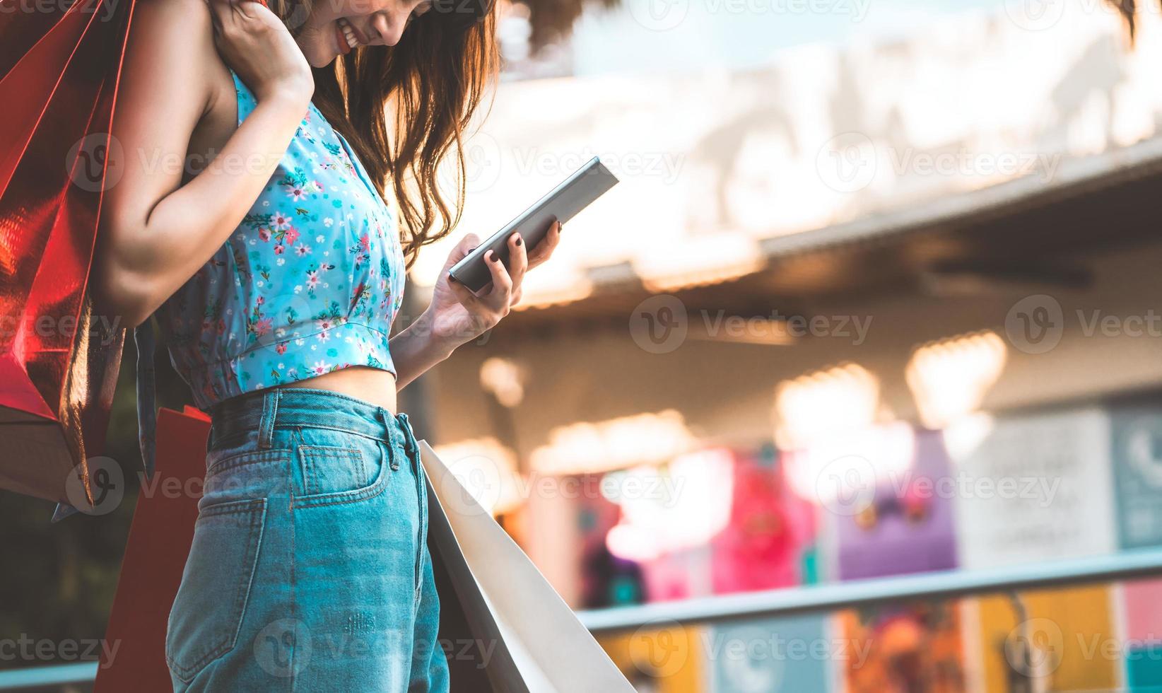 mujer asiática sostiene una bolsa roja y usa un teléfono inteligente foto