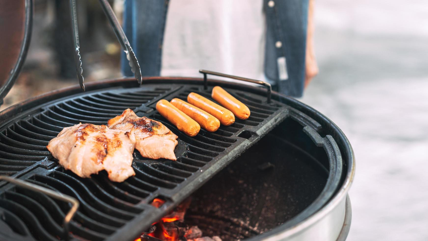 Man hand grilling barbecue on fire at backyard on day photo