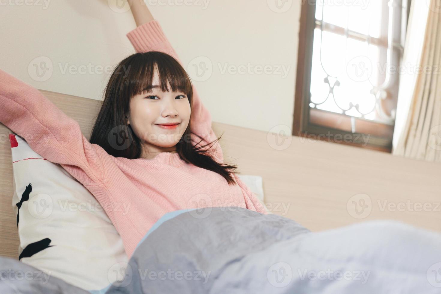 Wake up arm stretch asian teenager woman in bedroom. photo