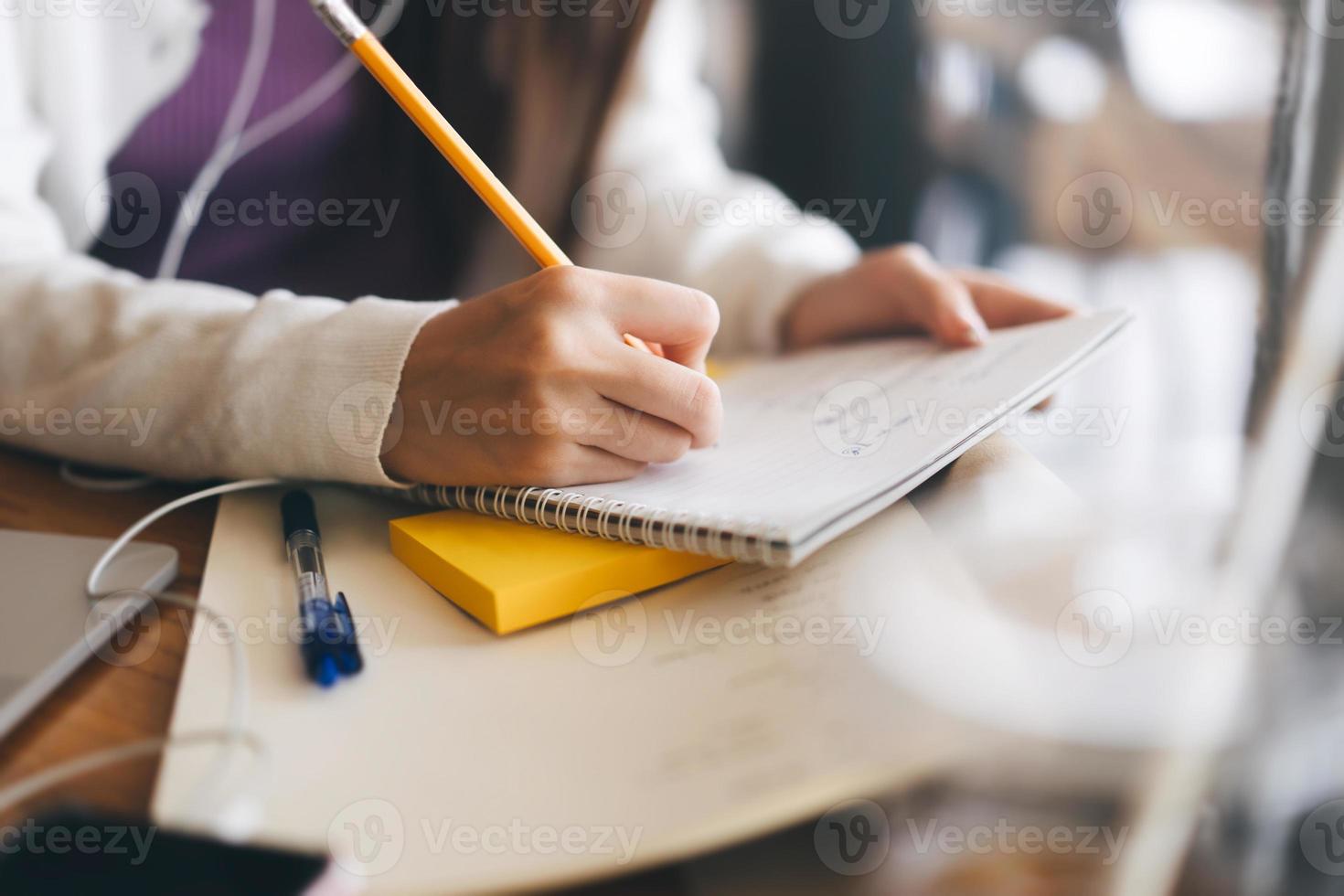 mujeres adultas jóvenes escriben a mano una nota para estudiar y trabajar en línea en la mesa de café con una computadora portátil. foto