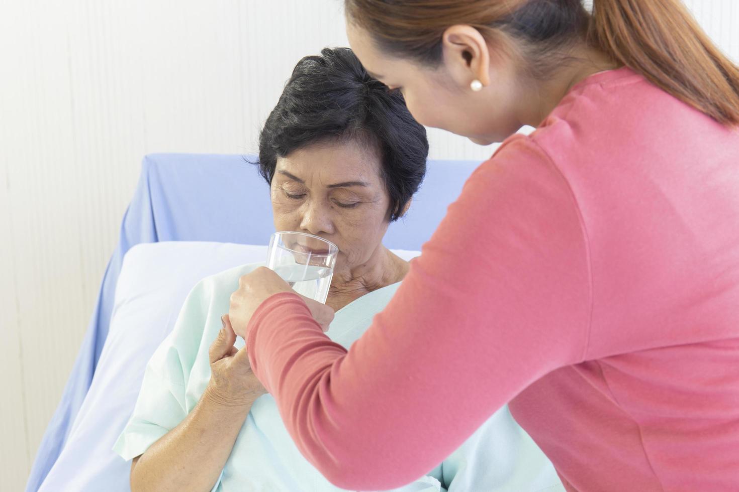 An Asian woman is taking care of her sick mother in a hospital bed. photo