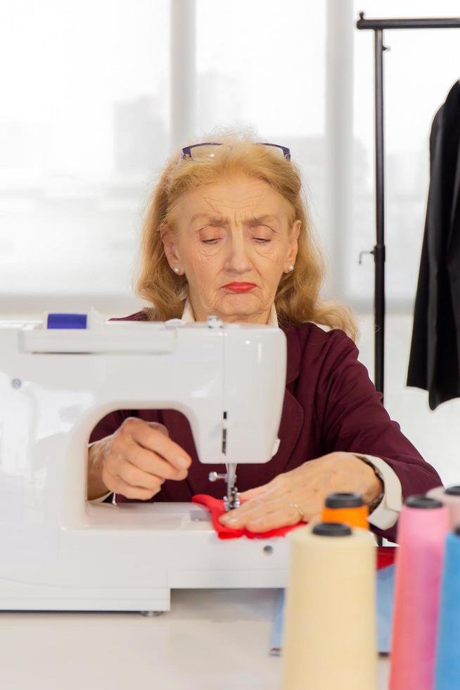 las diseñadoras profesionales están cosiendo con pequeñas máquinas de coser sobre la mesa. foto