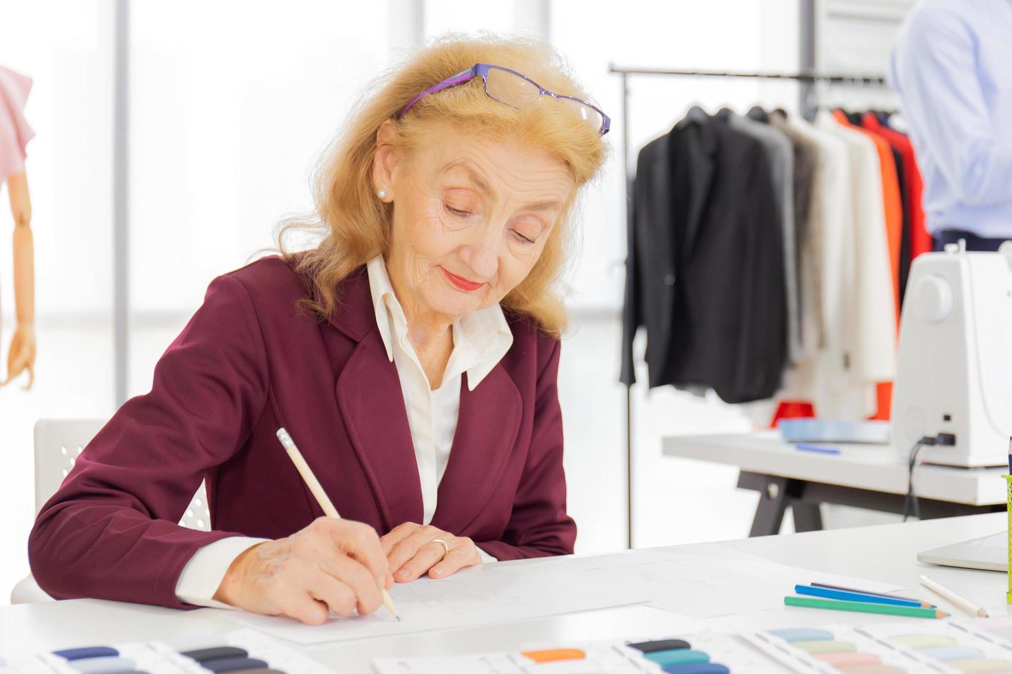 Professional female designers are drawing sketches on paper with pencils in a sewing room. photo