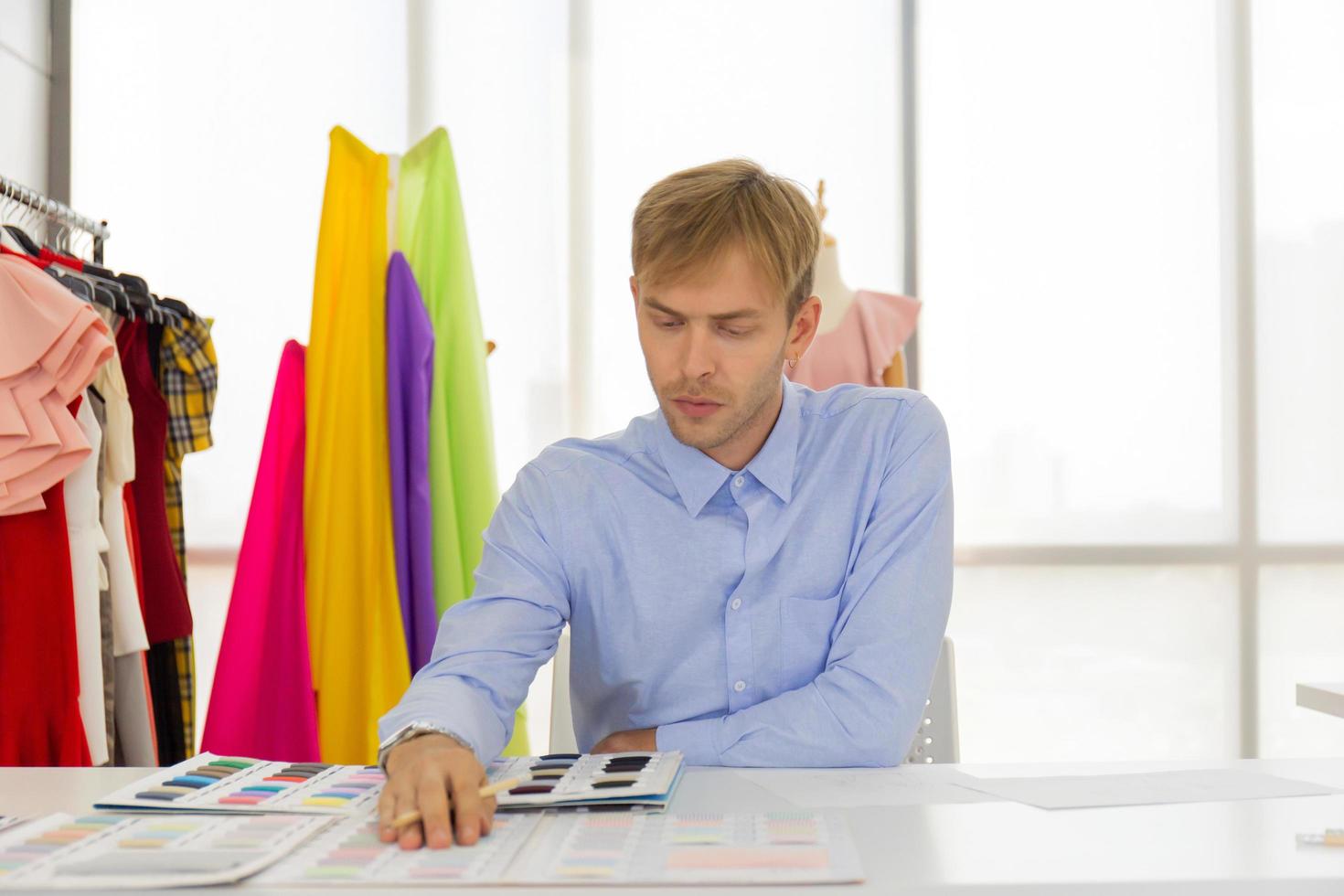 los diseñadores de costura masculinos profesionales en la oficina tienen una variedad de combinaciones de colores de tela. foto