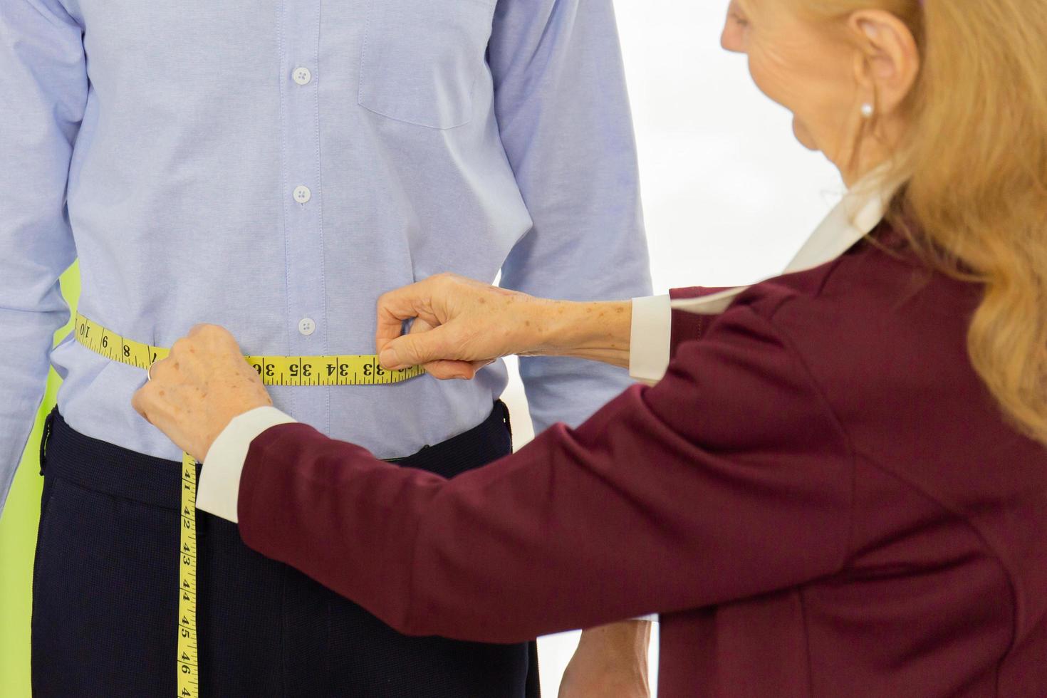 Professional female designers are measuring the size of male customers who use the service for tailoring. photo