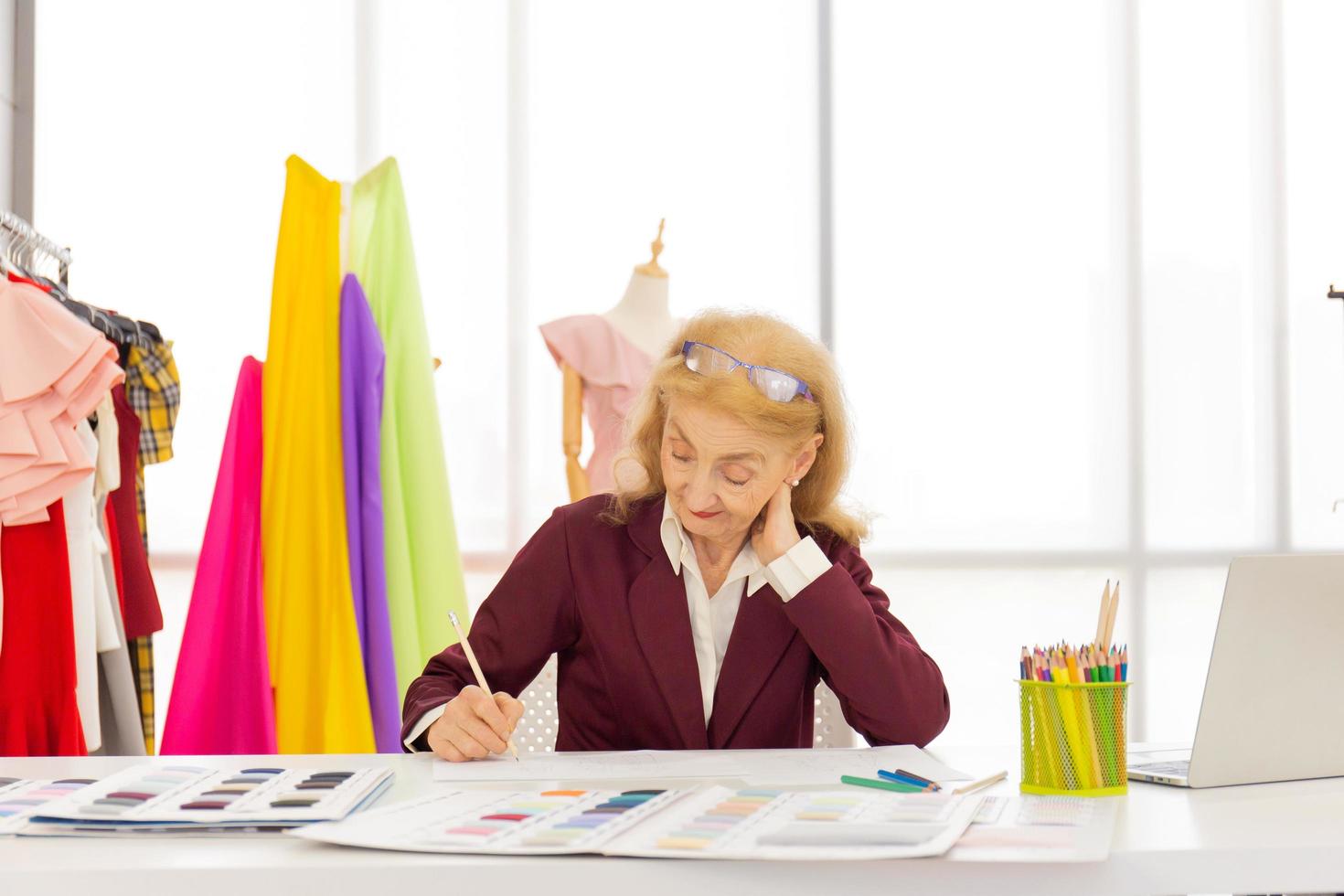 Professional female designers are drawing sketches on paper with pencils in a sewing room. photo