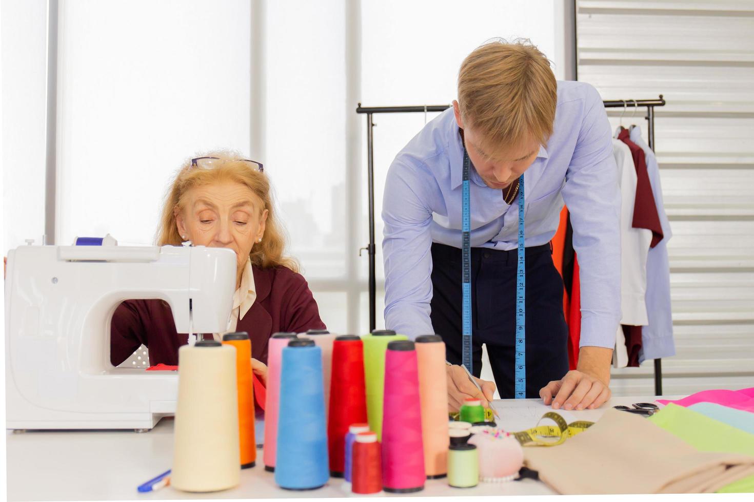 Professional team work designers, young men and elderly women in the office with a variety of fabric tones and equipment for various designs. photo