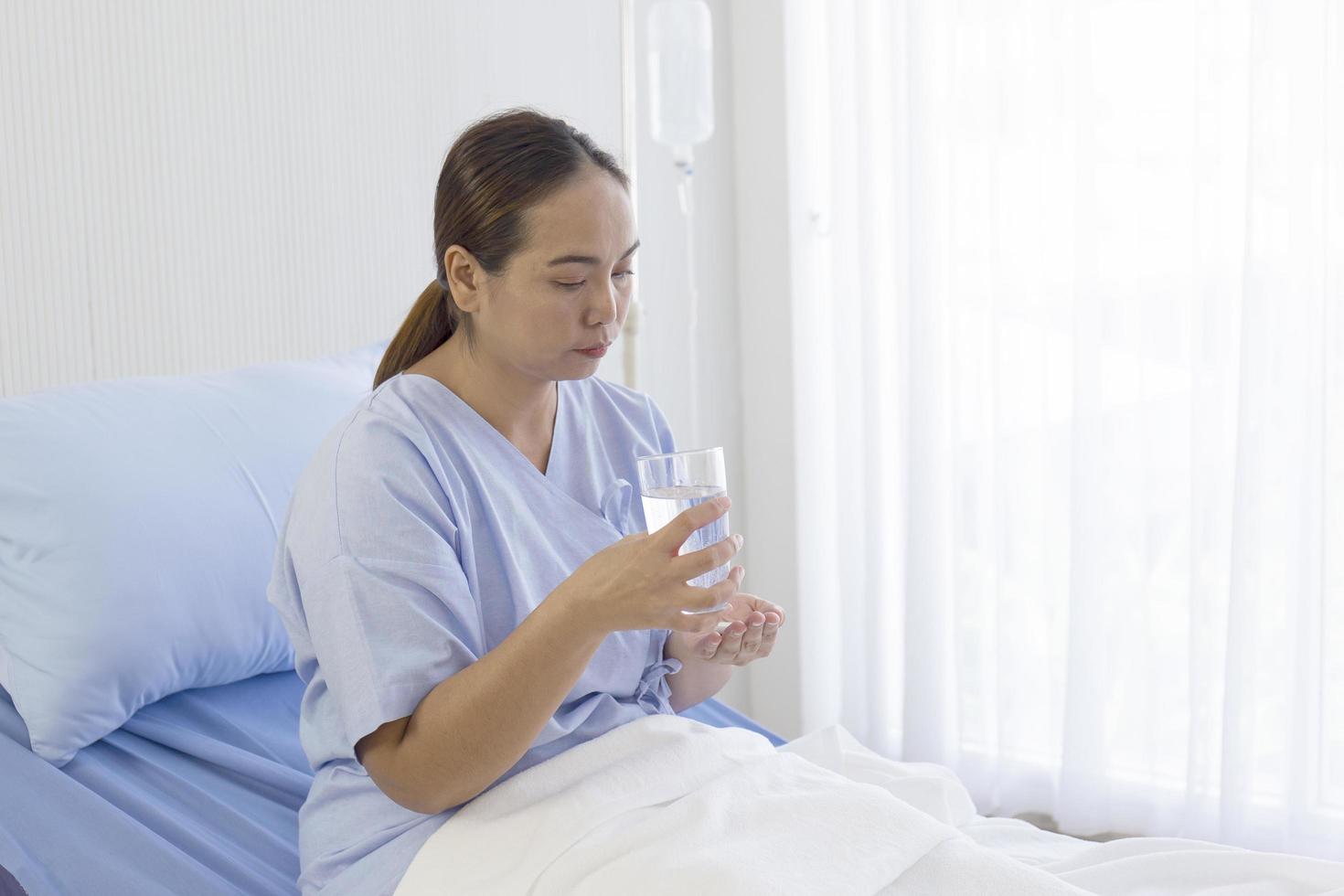 pacientes asiáticas sentadas en una cama comiendo medicinas en el hospital foto